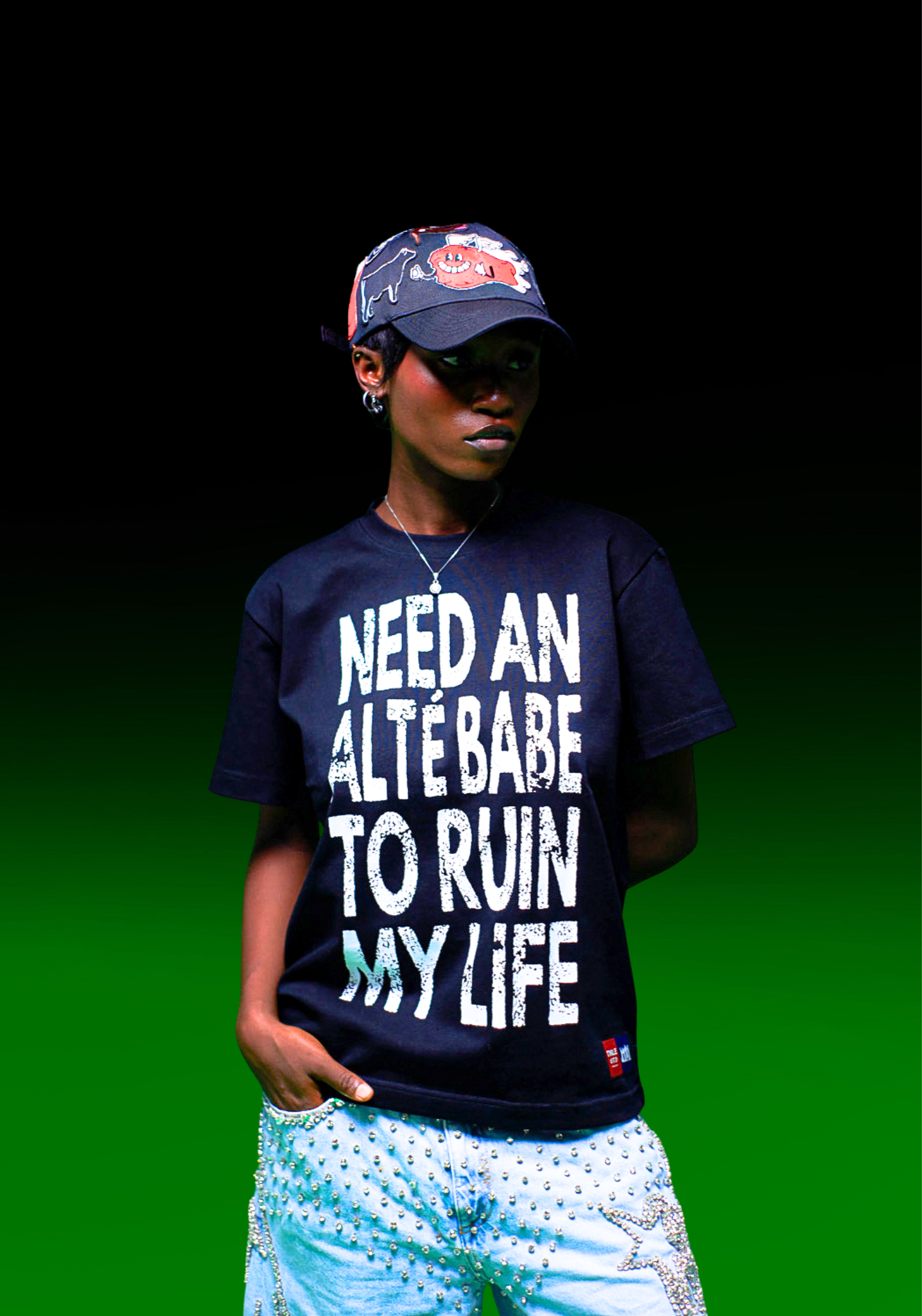 Person wearing a navy blue t-shirt with text and a cap on a gradient background